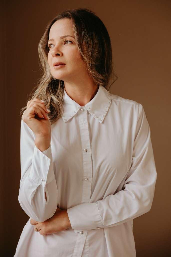 Larissa Lopes de camisa branca, olhando em direção à luz